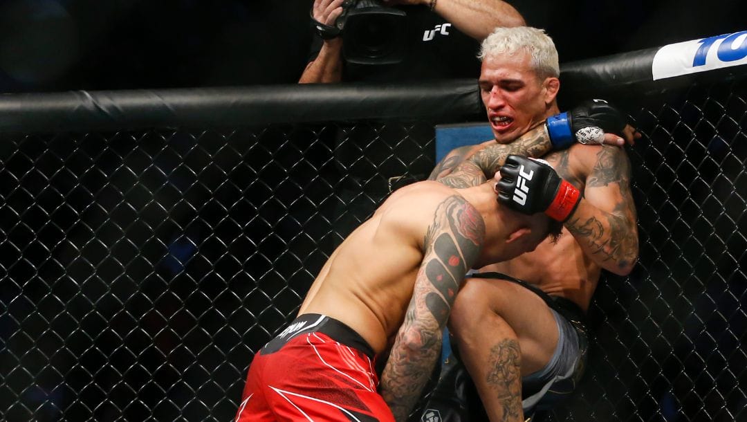 Charles Oliveira, right, delivers a knee to Dustin Poirier during a lightweight mixed martial arts title bout at UFC 269.