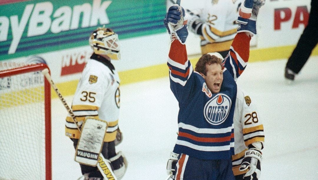 Craig MacTavish of the Edmonton Oilers, right, celebrates after Edmonton's Petr Klima scored the game-winning goal against Boston Bruins goalie Andy Moog, left, in the third overtime period of the Stanley Cup final series game at Boston early, Wednesday, May 16, 1990. Edmonton beat Boston 3-2 to take a 1-0 lead in the best-of-seven series.
