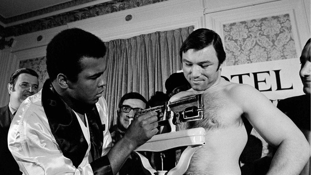 Muhammad Ali adjusts the scale for Toronto’s George Chuvalo at their weigh-in on May 1, 1972 in Vancouver.