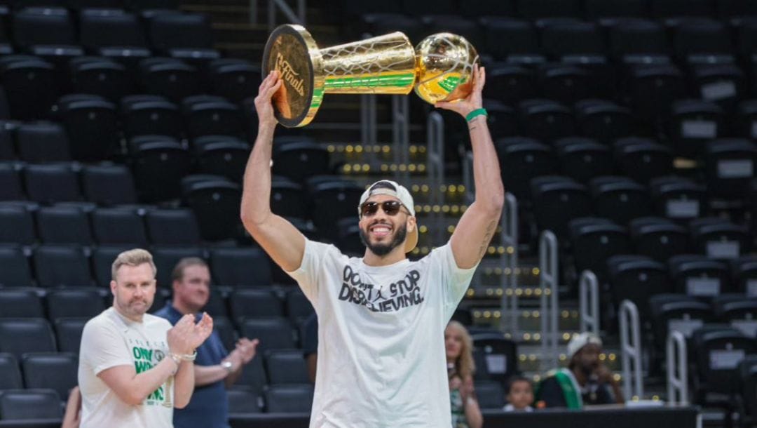 Boston Celtics star Jayson Tatun holding the 2024 NBA title.