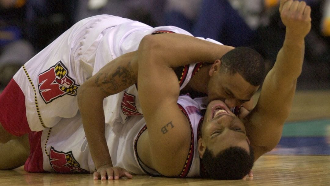 Maryland's Juan Dixon falls on top of teammate Lonny Baxter after defeating Indiana 64-52 to win the NCAA final in Atlanta.