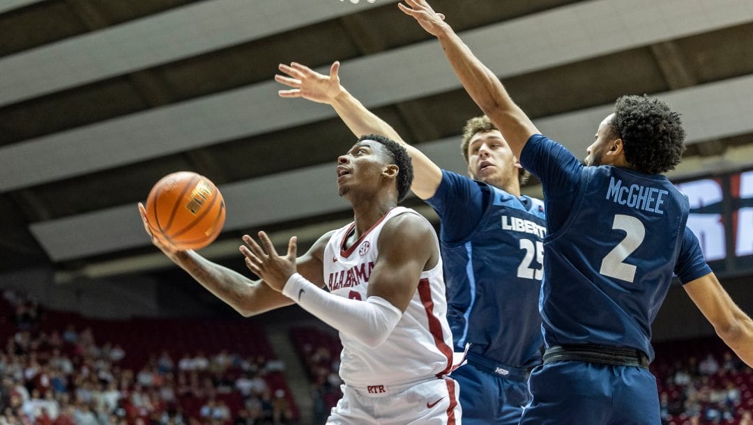 Alabama guard Jaden Bradley (0) gets inside between Liberty forward Zach Cleveland (25) and guard Darius McGhee (2) for a shot during the second half of an NCAA college basketball game, Friday, Nov. 11, 2022, in Tuscaloosa, Ala.