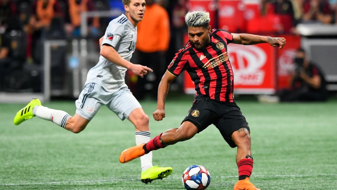 FILE - Atlanta United forward Josef Martinez (7) kicks a shot on goal as New England Revolution midfielder Scott Caldwell.