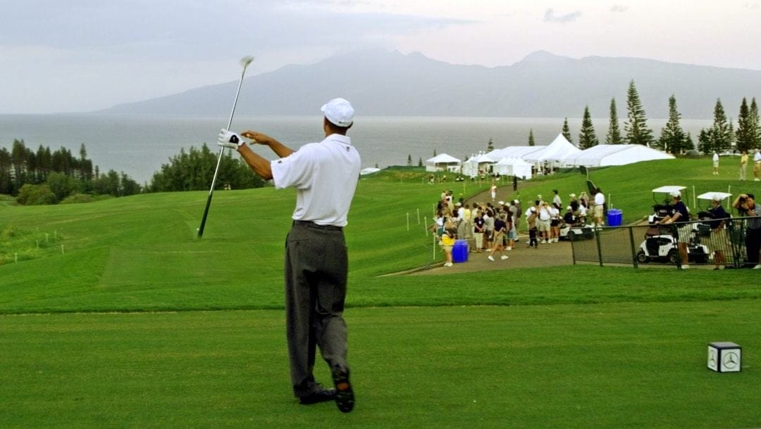 Tiger Woods follows his drive from the first tee of the Plantation Course at dawn with the island of Molokai in the background during the pro-am of the Mercedes Championships in Kapalua, Hawaii Wednesday Jan. 2, 2002. First round play begins Thursday in the season opening event of the PGA Tour.