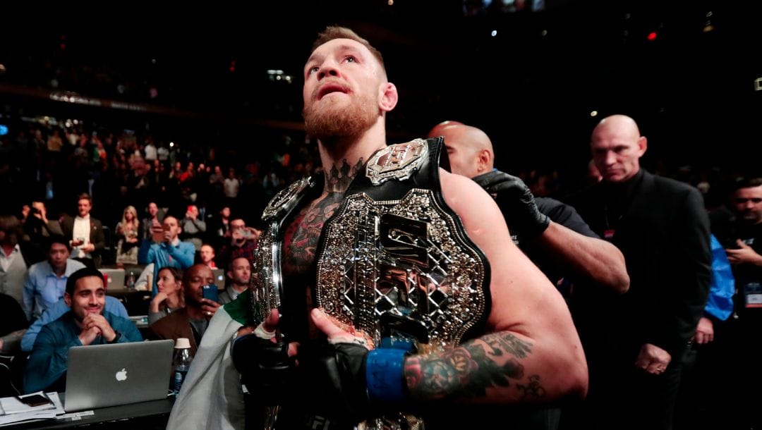 FILE - In this Nov. 13, 2016, file photo, Conor McGregor leaves the octagon with his title belts after knocking out Eddie Alvarez.