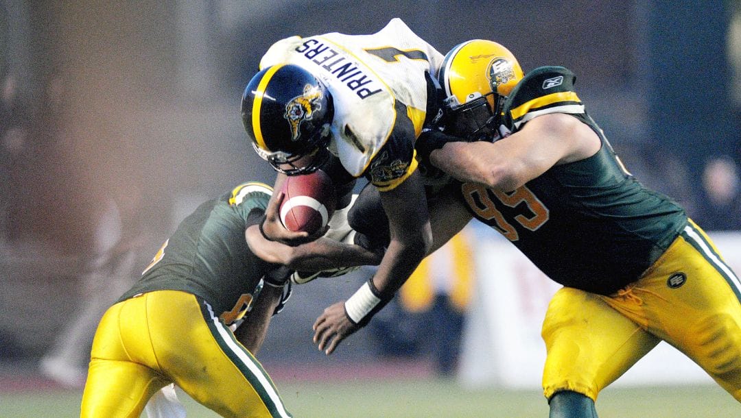 Hamilton Tiger-Cats quarter-back Casey Printers diving over Edmonton Eskimos' Jason Goss, left, and Montez Murphy.