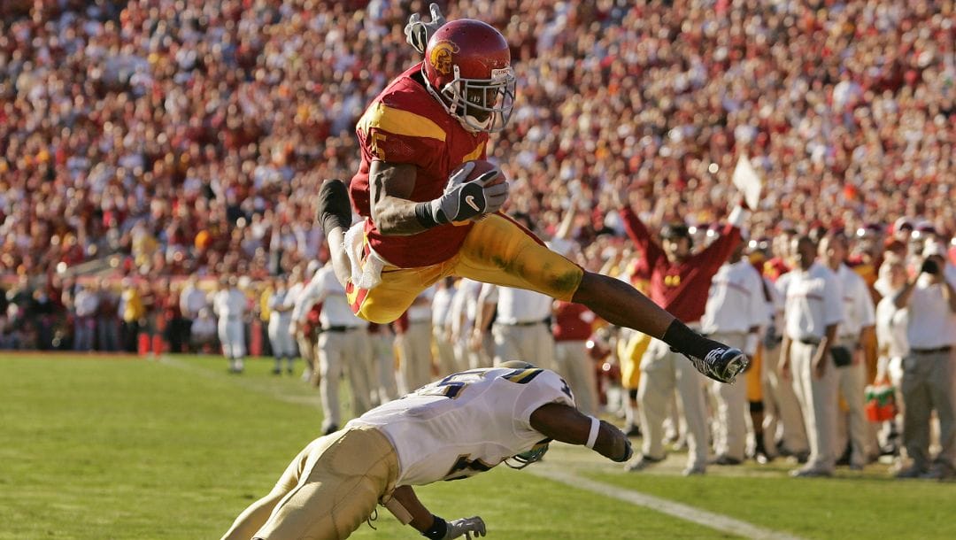 FILE - In this Dec. 3, 2005, file photo, Southern California's Reggie Bush leaps over UCLA defender Marcus Cassel as he rushes.