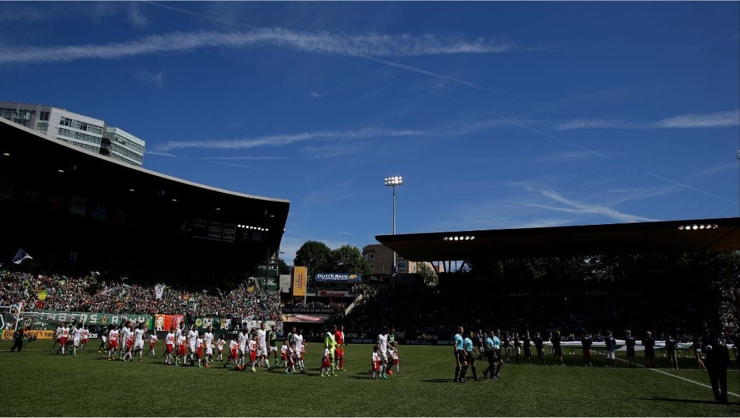 Seattle Sounders and Portland Timbers players follow referees into Providence Park at the start of an MLS soccer match.