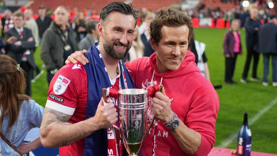Wrexham co-owner Ryan Reynolds, right, and Wrexham's Ollie Palmer pose with trophy at the end of the English League One soccer.