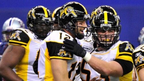 Hamilton Tiger-Cats quarterback Quinton Porter celebrates after scoring a touchdown against the Montreal Alouettes with teammate.