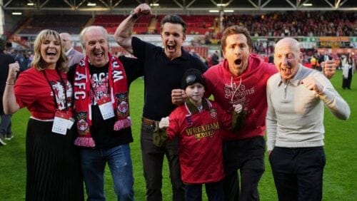 Wrexham co-owners Rob McElhenney, center, and Ryan Reynolds, second right, celebrate at the end of the English League One soccer match between Wrexham and Charlton Athletic at the Racecourse ground in Wrexham, Wales, Saturday, April 26, 2025.